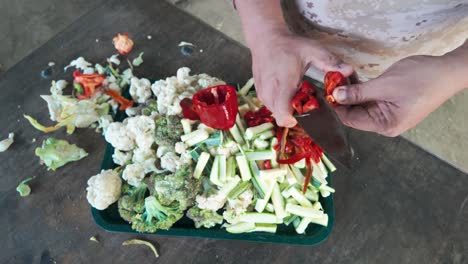 Top-down perspective of vibrant mixed vegetables being cut on a tray