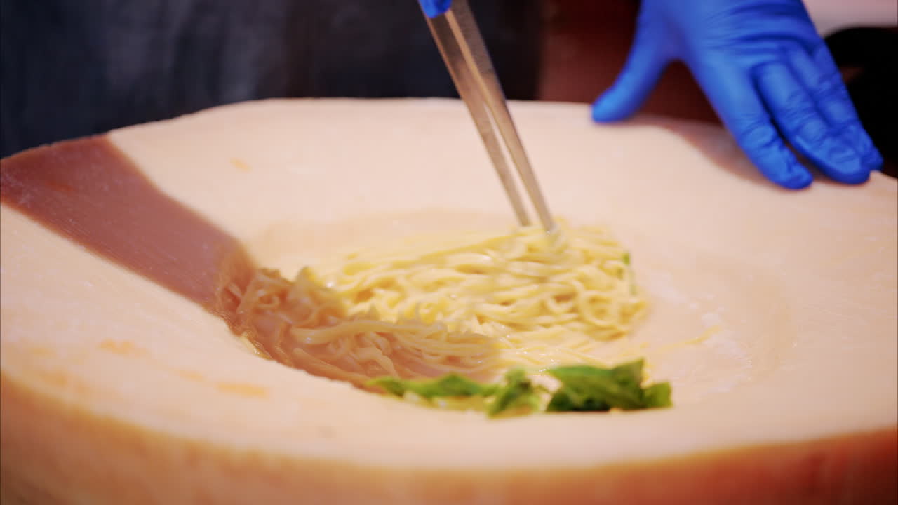 Man mixing pasta in a heated parmesan wheel at a restaurant