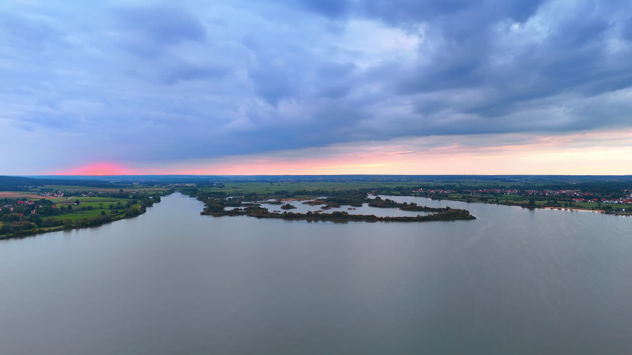 Aerial view of countryside and cloudy sky at dusk. Drone shot of rural fields and distant hills under dramatic evening clouds