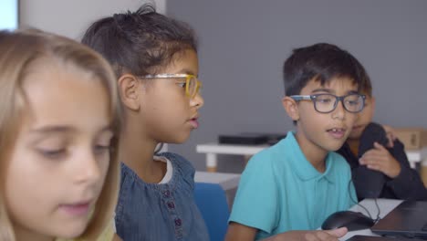 Smart-schoolboy-in-glasses-helping-classmates-to-do-task