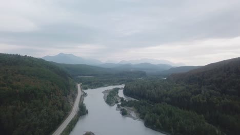 Aerial-view,-drone-flight-along-the-Glenn-Highway-and-the-Matanuska-River-in-the-Chugach-Mountain-Range-of-central-Alaska-on-a-cloudy-summer-day