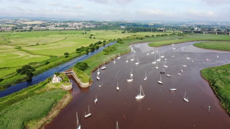 Vista-Aérea-Escénica-De-Veleros-Anclados-En-El-Río-Exe-Junto-A-Campos-Verdes