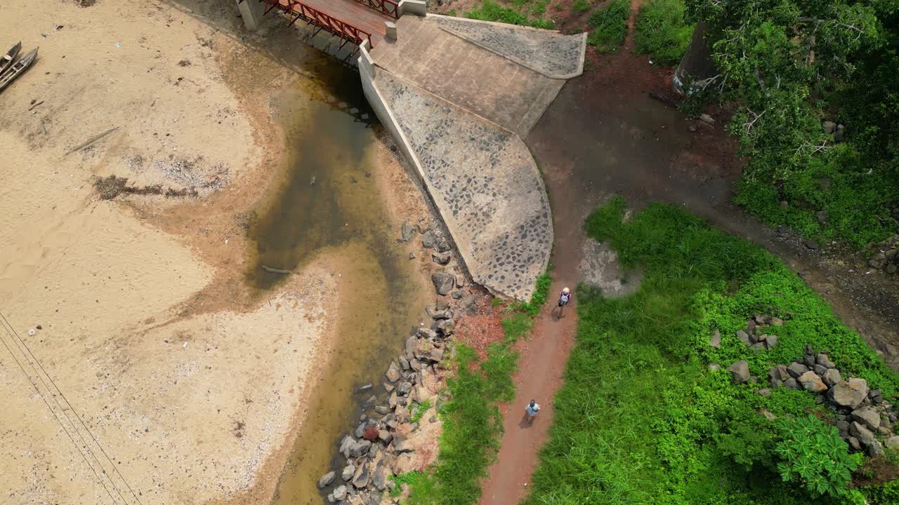 Seen from above a couple walking along the coast arriving at Morro Peixe village in São Tomé,Africa