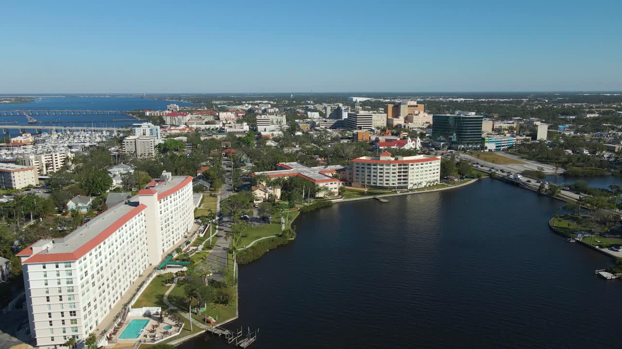 Aerial drone footage of Bradenton Florida showcasing the downtown skyline, riverfront, and bridges under clear blue skies. Wide Crane Down E
