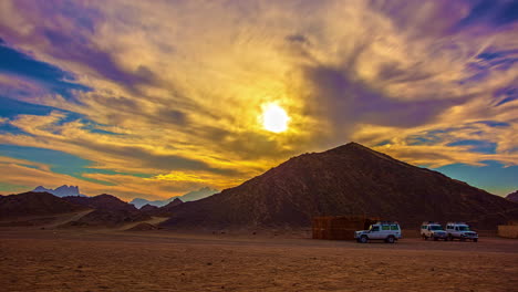 People-And-Safari-Tour-Vehicle-In-Desert-Mountains-Against-Dramatic-Golden-Sky