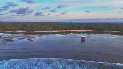 panning drone shot de la bahía de g-land, también conocida como playa de plengkung, que muestra una densa jungla, arrecife de coral, campamento en la costa y torre de observación