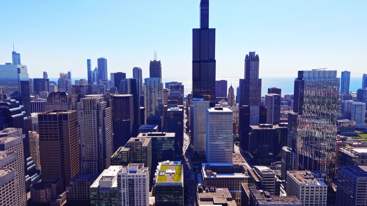 Arranha-céu preto alto erguendo-se acima dos edifícios do centro com o Lago Michigan no horizonte. Vista aérea da Willis Tower e do horizonte de Chicago, Illinois