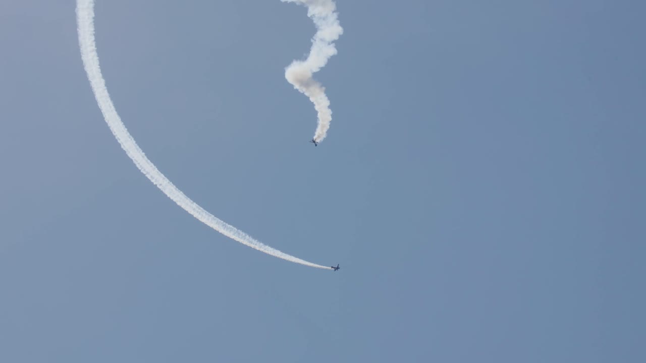 두 대의 스턴트 비행기, 하나는 나선형 스톨에 있고, 하나는 주위를 돌고 있습니다.