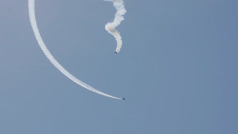 two stunt planes, one in a spiral stall, and one circling around it