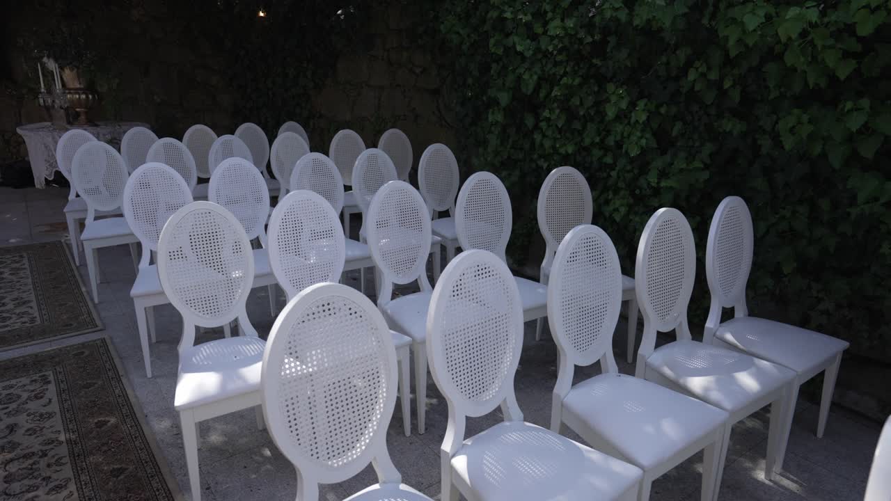 White chairs arranged in a garden setting for an outdoor event.