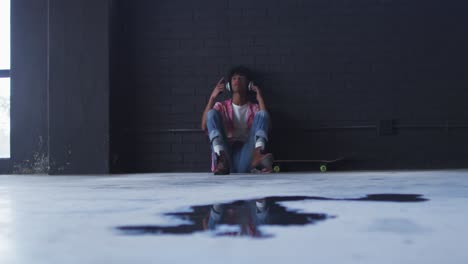 african american man wearing headphones listening to music while sitting in empty parking garage