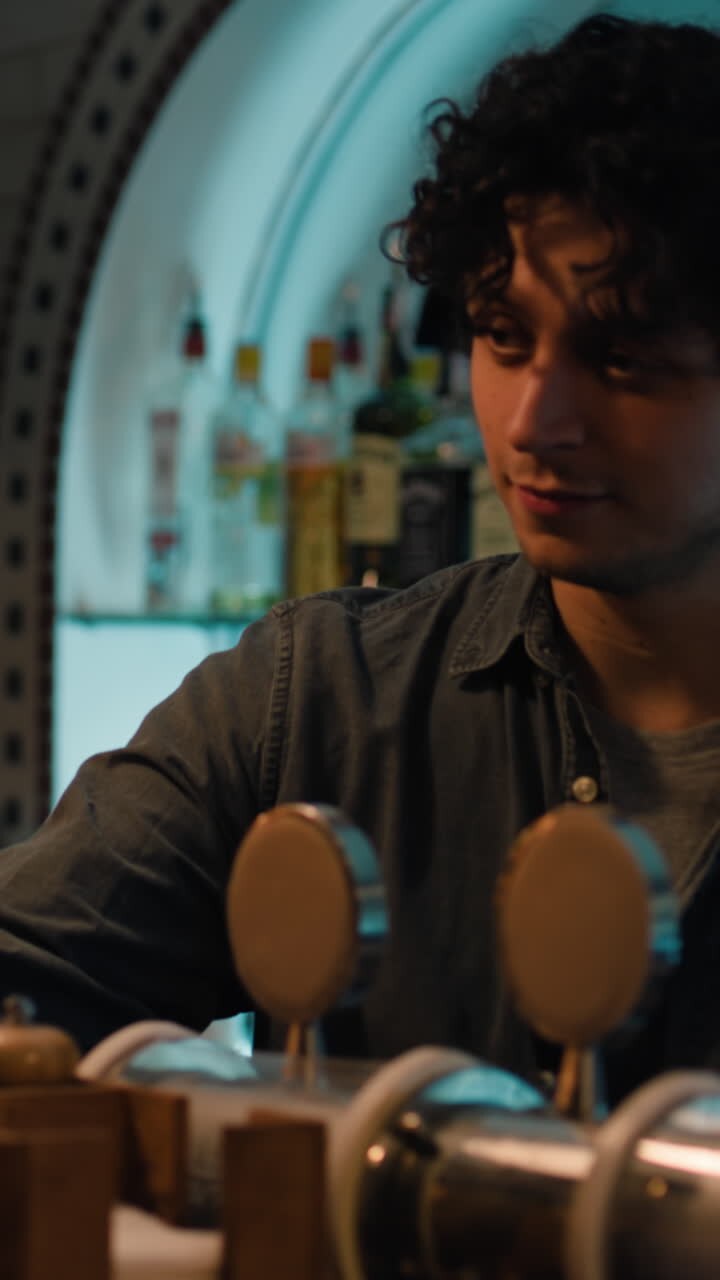 il barman prende gli ordini, comunica con le persone sedute al bancone del bar, lavora in un elegante pub di notte. concetto di stile di vita e tempo libero.