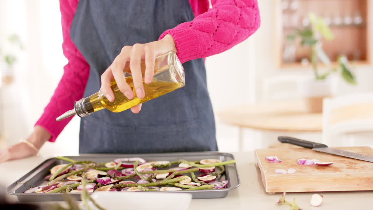sección media de una mujer biracial preparando comida en la cocina en casa con espacio de copia, cámara lenta