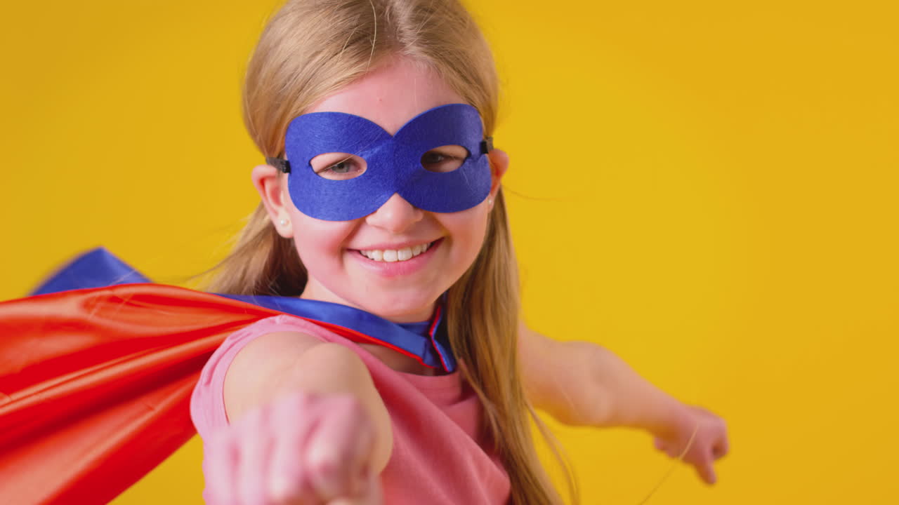 retrato de estudio de una niña vestida como superhéroe de cómics contra un fondo amarillo