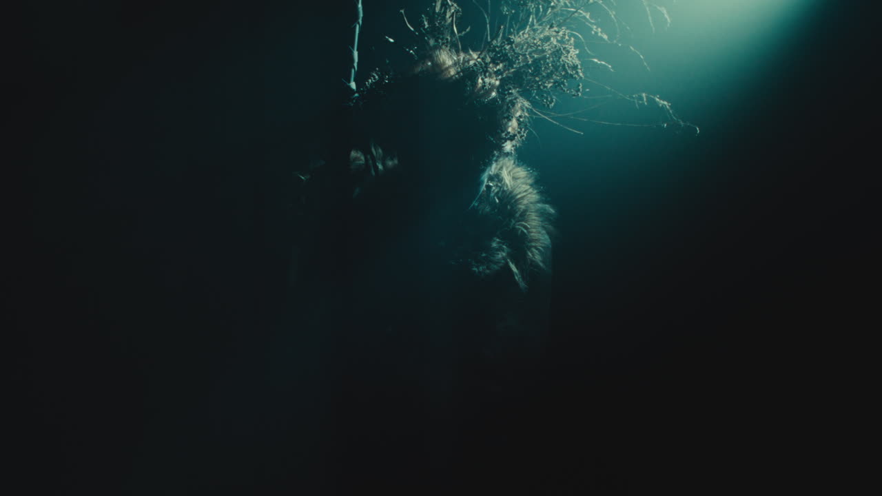 A creepy witch stands in the moody pose during the night storm