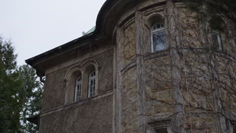 camera tilting upwards to reveal the front of an old, abandoned castle in germany with walls clad in ivy