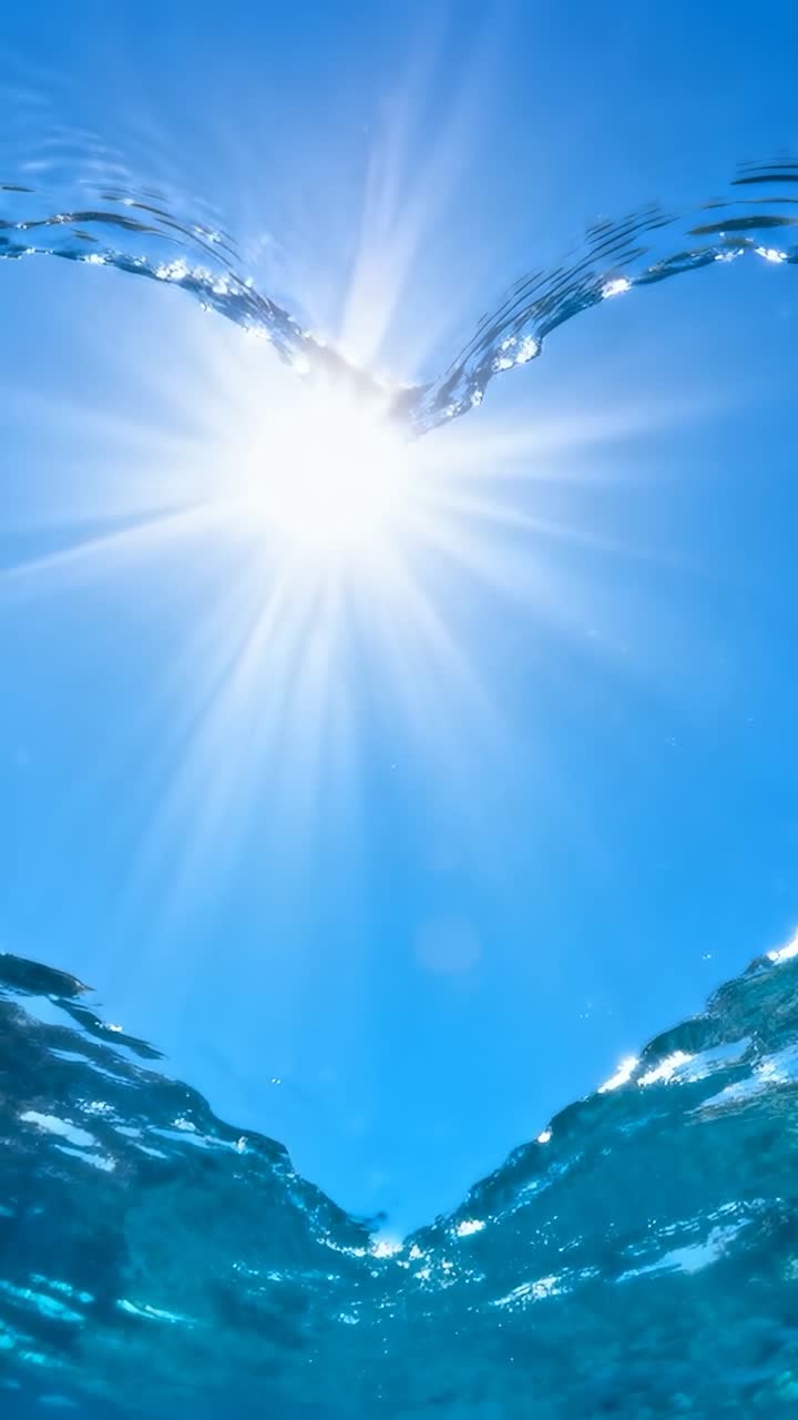 縦型動画：V字型の波頭が盛り上がり、海面が二層に分かれて見える。太陽と太陽光線。