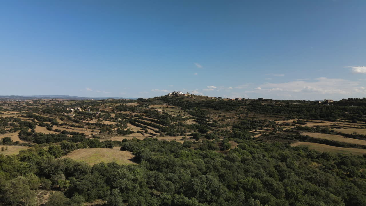 casa en lo alto de la colina rodeada de un bosque profundo y unos campos en lleida