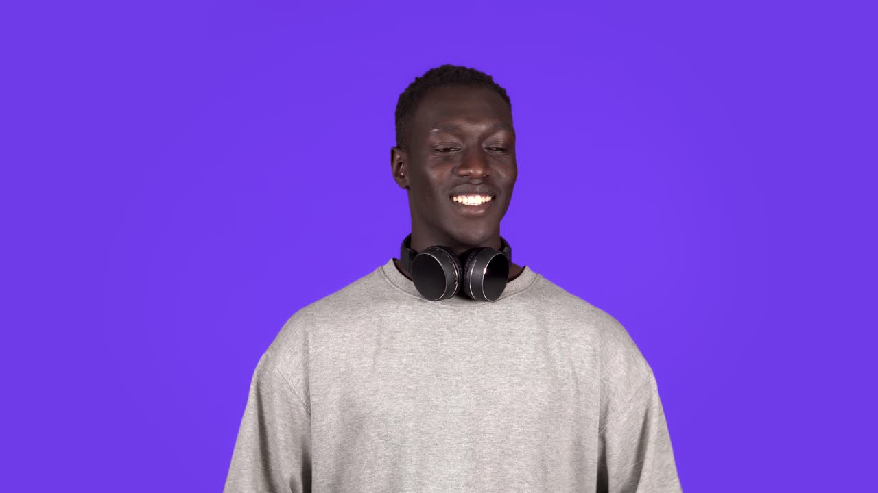 Attractive joyful young african man looking to the camera in headphones on neck smile happy talks at camera. Positive emotions. Male portrait. Contemporary human