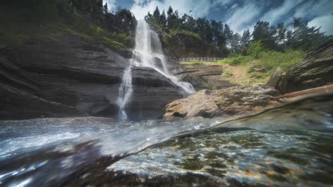 soothing sight of a river's rocky shores and transparent waters, with a waterfall in the background