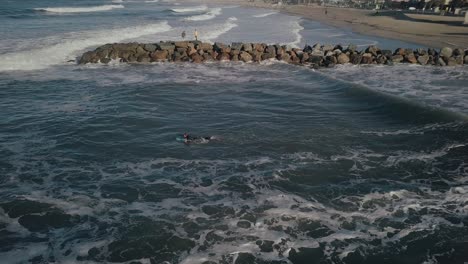 vista aérea de drones de un surfista que se dirige sobre las olas del océano frente a la costa de venice beach