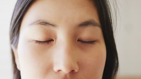 Portrait-of-happy-asian-woman-opening-her-eyes-and-looking-at-camera