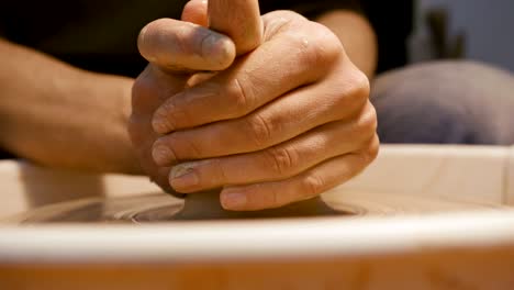 man's hands making clay ware on the potter's wheel