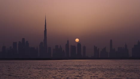 Luna-Llena-Sobre-El-Horizonte-De-Dubai-Con-Dubai-Creek-En-La-Noche-Dubai,-Emiratos-árabes-Unidos,-Oriente-Medio