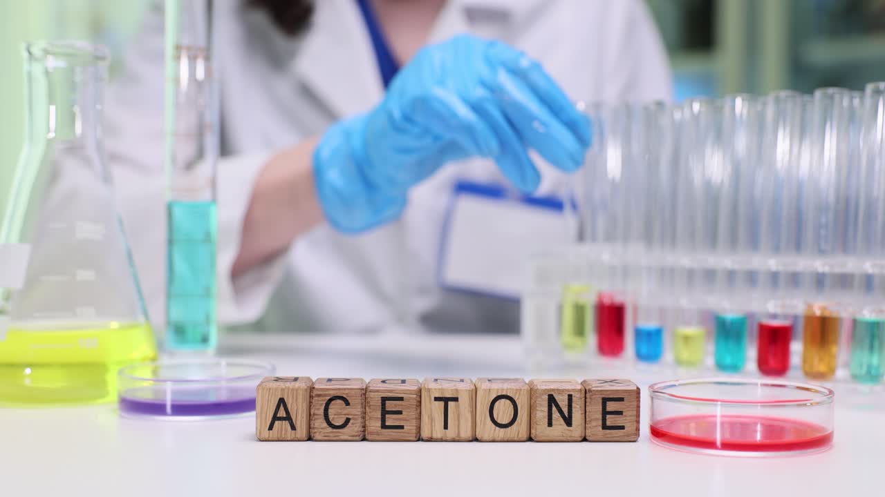 Blocchi di legno formano la parola acetone vicino a provette in laboratorio