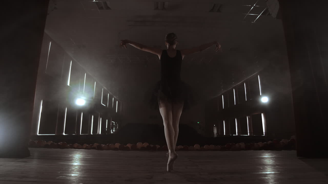 A ballerina dances in a hall with empty seats. A female dancer enjoys the quiet of an empty scene and no audience