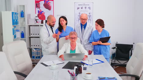 equipo de médicos mirando la computadora portátil en la sala de conferencias discutiendo