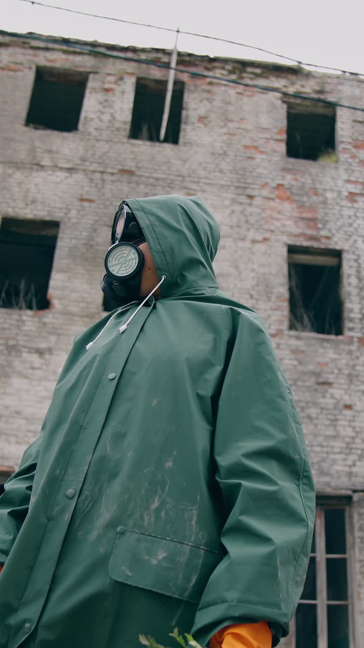 Environmentalist in protective suit and gas mask. Man in gas mask near abandoned destroyed building
