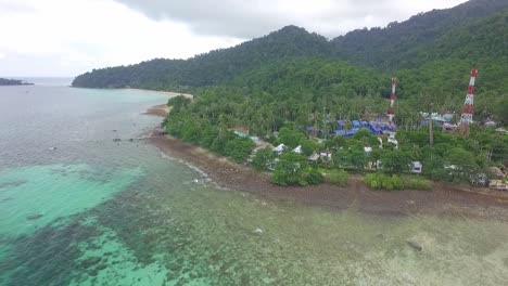 toma de drones de una isla tropical con playa, costa rocosa, pequeños complejos de bungalows y torres de telecomunicaciones