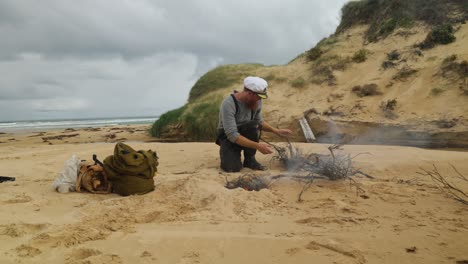 a-1900s-sailor-starts-a-fire-along-the-coastline-while-setting-up-camp