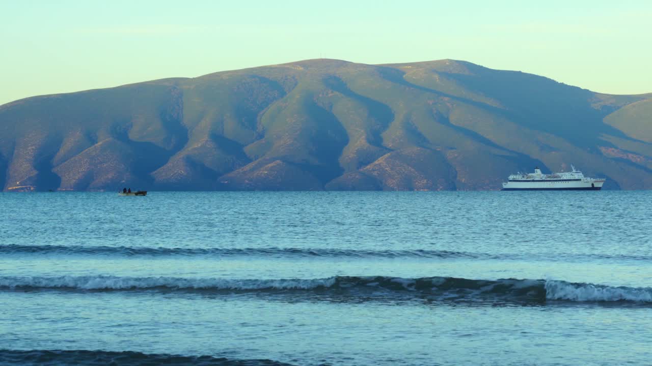 해안 근처의 바닷물에 떠 있는 어선과 함께 일출 때 어부들, 항구를 향해 천천히 접근하는 흰색 페리