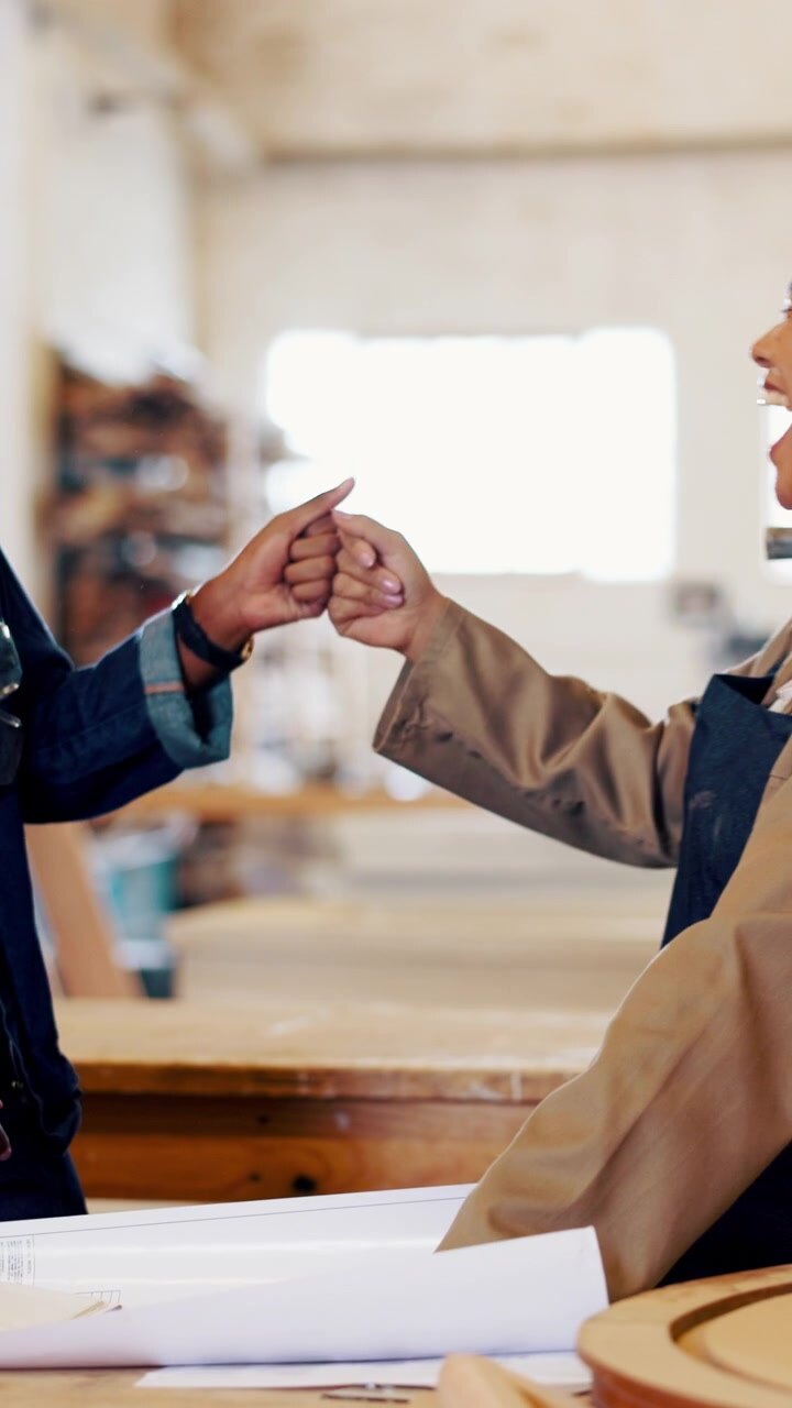 Two Female Carpenters Celebrating Success with a Fist Bump in Workshop