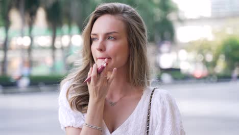 mujer aplicando lápiz labial al aire libre