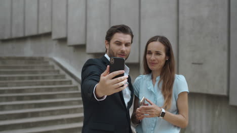 compañeros de trabajo exitosos que usan teléfonos celulares para videollamadas en la calle urbana