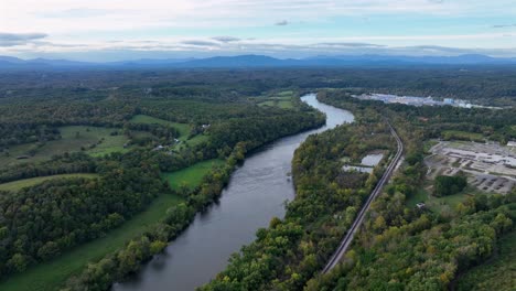 aerial establishing shot of river surrounded by green american nature during sunrise in autumn. wide shot.