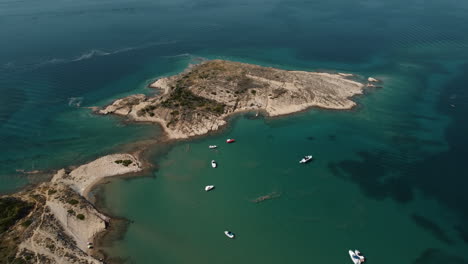 Aerial-View-of-Boats-Anchored-by-Picturesque-Coastline-of-Rab-Island,-Croatia-on-Sunny-Summer-Day,-Drone-Shot