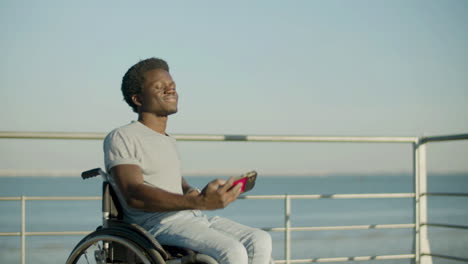 Young-Guy-In-Wheelchair-Taking-Selfie-Against-Sea-Background