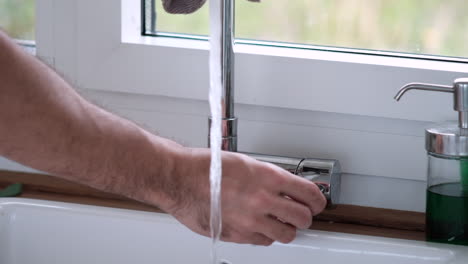 turning on faucet: clean water rushing into sink close-up hand action