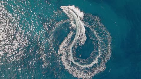 a motor boat in the blue sea turns a symbol in slowmo