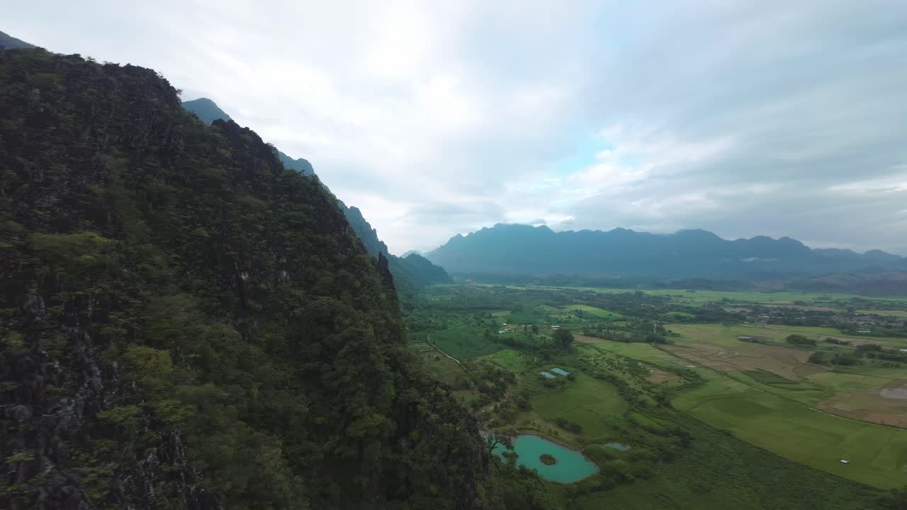Scenic aerial view over the Blue Lagoon in Laos, with green forests, river bends, and rugged cliffs surrounding the water