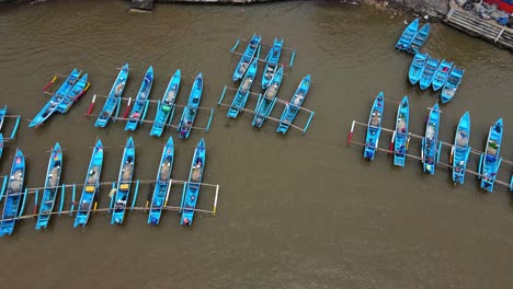 aerial top down shot traditional blue colored fisherman parking at harbor of baron beach, yogyakarta, indonesia