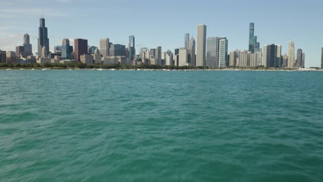 Vista-De-Pájaro-Baja-Sobre-El-Agua-Entrecortada,-Horizonte-De-Chicago-En-Segundo-Plano