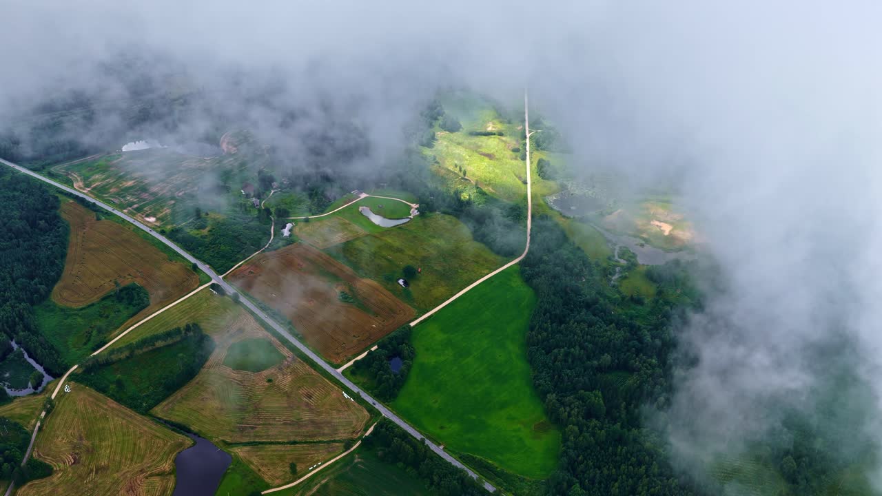 Top drone shot of partial view of agriculture fields by clouds in a countryside