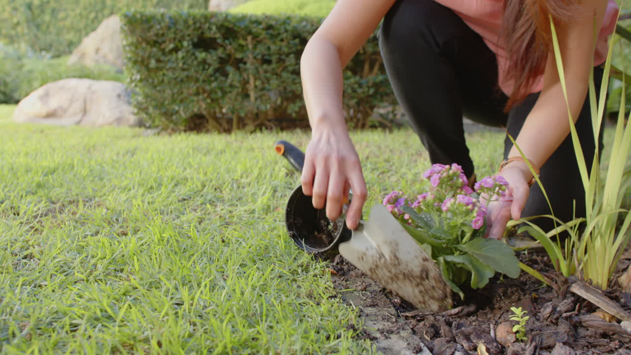 Gardening together, woman watering plants while another woman tends to garden