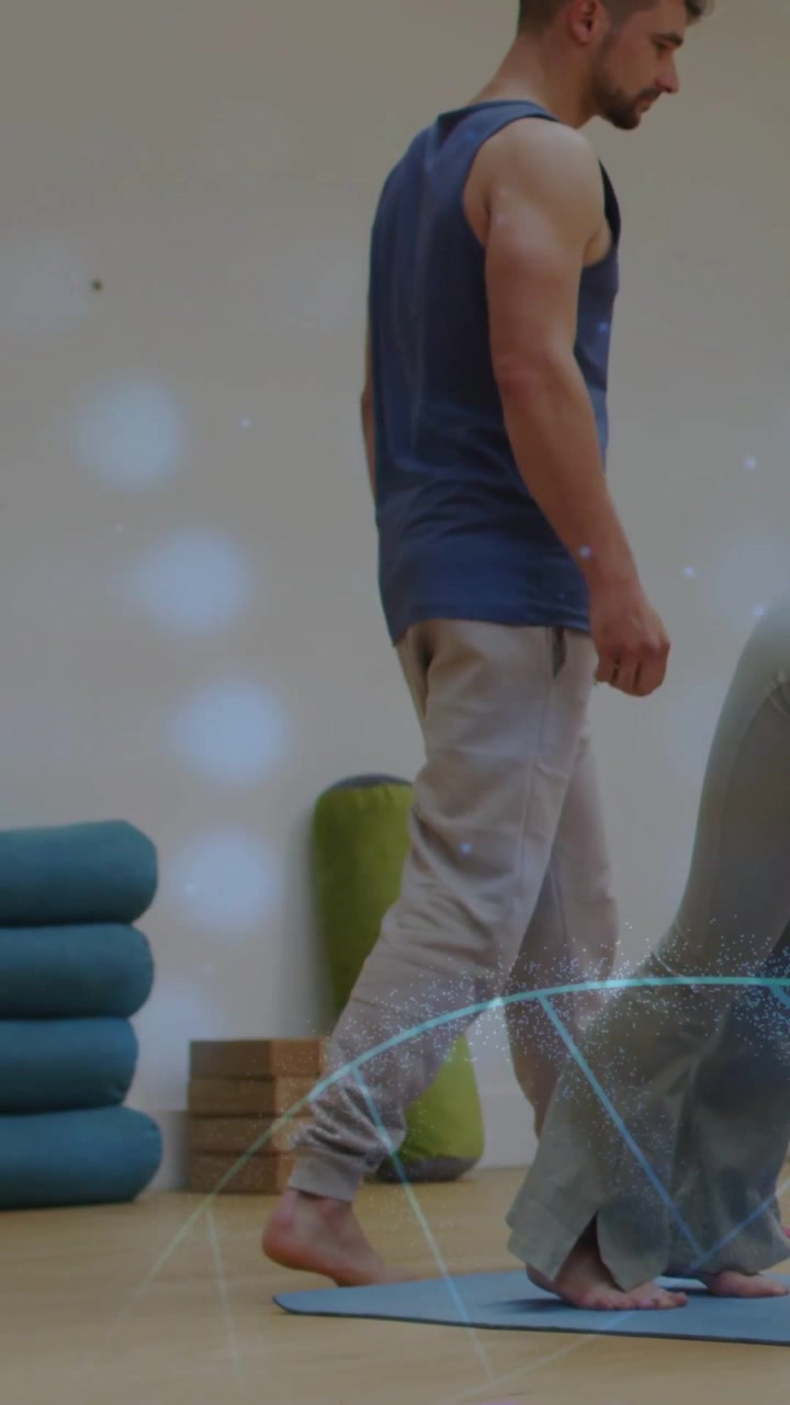 Vídeo vertical: Treinador andando ao lado de tapete de yoga, guiando aluno(a) mantendo a dobra para manter a pose perto de blocos