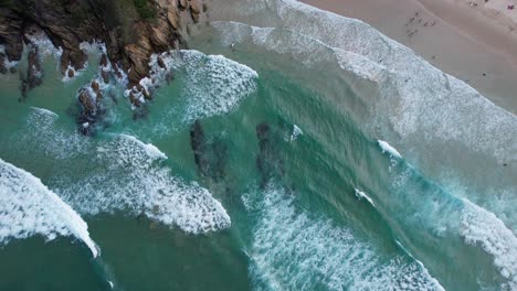 bird's eye view of ocean waves splashing at broken head beach in nsw, australia - drone shot